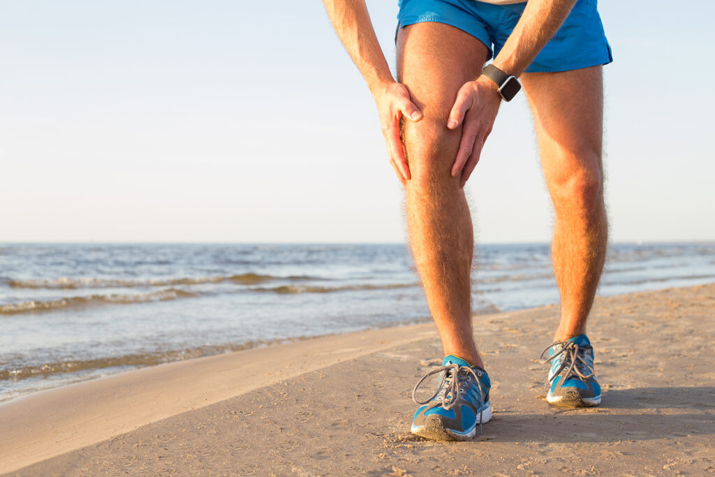 A man in running attire clutching his knee in an outdoor setting