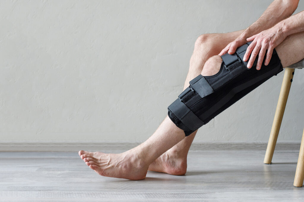 A patient with a knee brace on while sitting on a chair