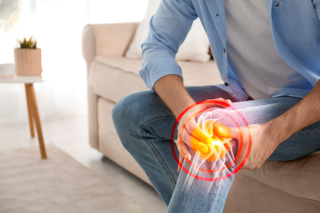 A man clutching his knee with a red glow indicating pain or discomfort
