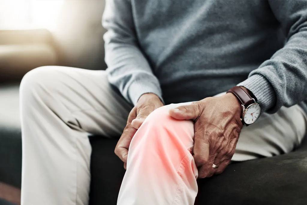 A man clutching his knee with a soft red glow indicating pain from knee arthritis
