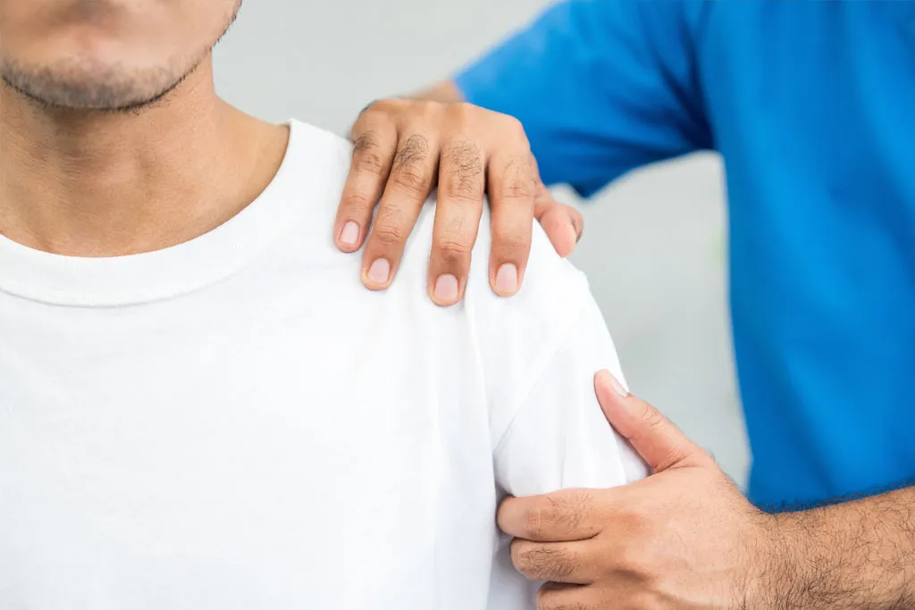 A medical professional assessing a man’s shoulder