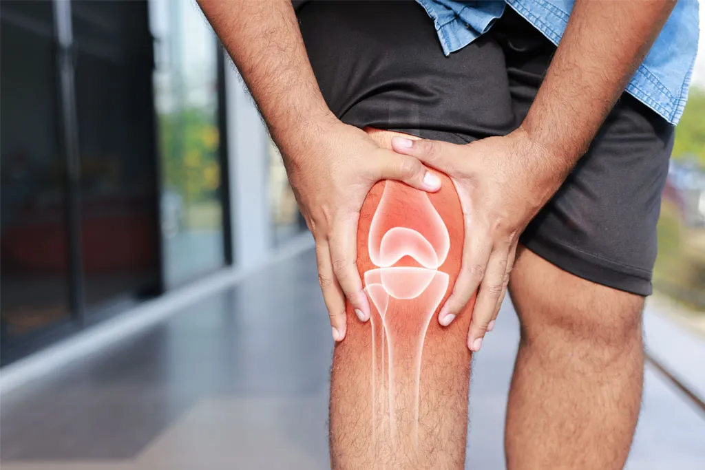 A man clutching his knee with a soft red glow indicating knee pain or discomfort