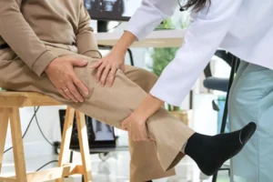 Doctor examining senior patient for osteoarthritis and knee pain during orthopedic checkup in hospital