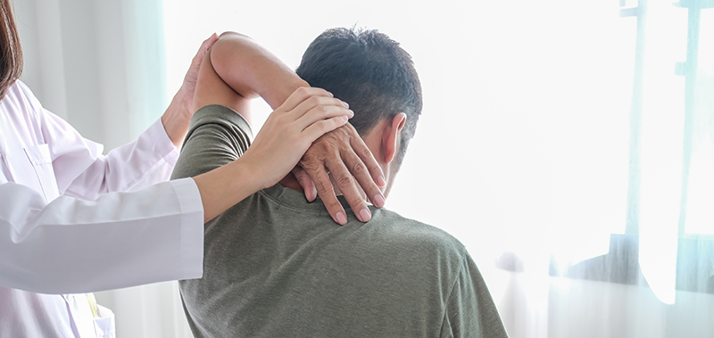 Orthopaedic specialist assessing shoulder range of motion during examination of a patient with persistent frozen shoulder symptoms